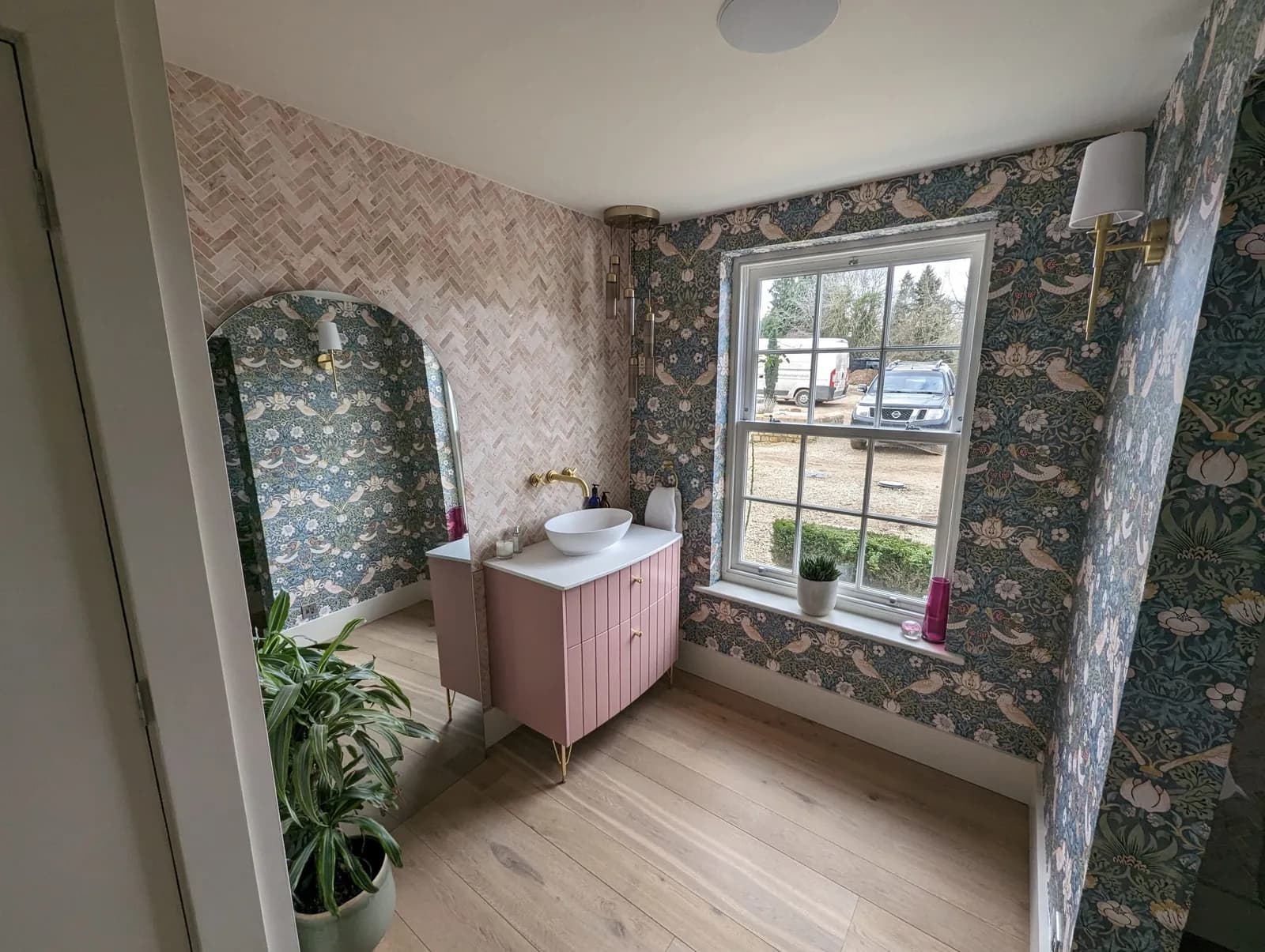 Renovated bathroom with botanical wallpaper and a pink vanity