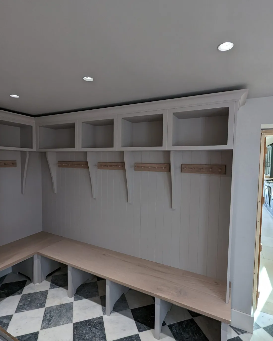 Bespoke boot room joinery with bench seating and a chequered floor