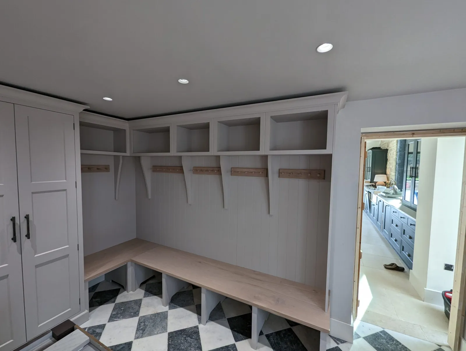 Bespoke boot room joinery with bench seating and a chequered floor